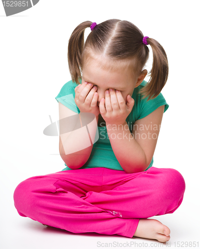 Image of Little girl is sitting on floor and crying