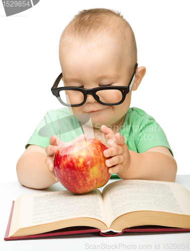 Image of Little child is playing with red apple