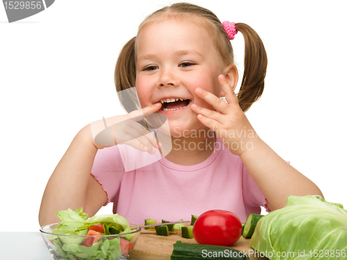 Image of Little girl is cutting carrot for salad