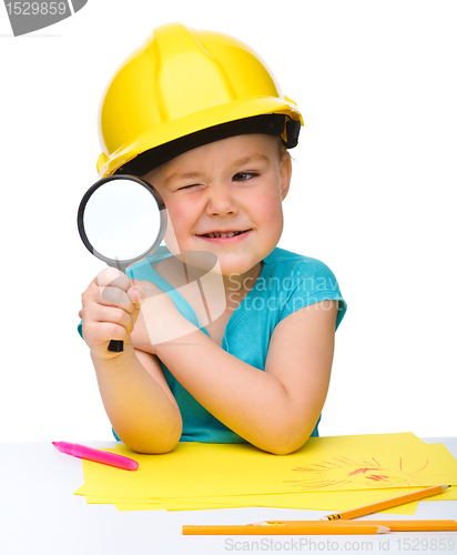 Image of Cute little girl is looking through magnifier