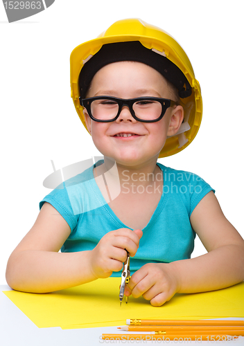 Image of Little girl is playing while wearing hard hat