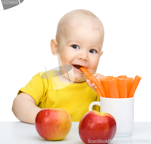 Image of Cute little boy eats carrot and apples