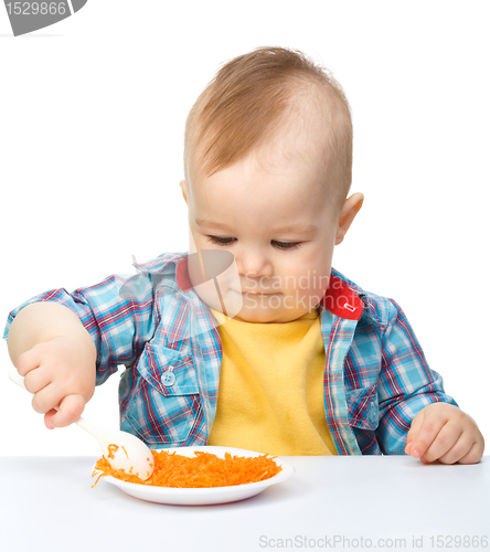 Image of Cute little boy is playing with carrot salad