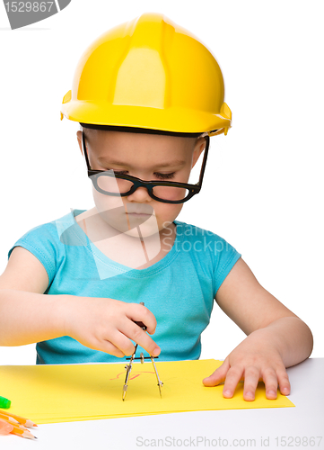 Image of Little girl is playing while wearing hard hat