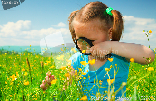 Image of Little girl examining flowers using magnifier