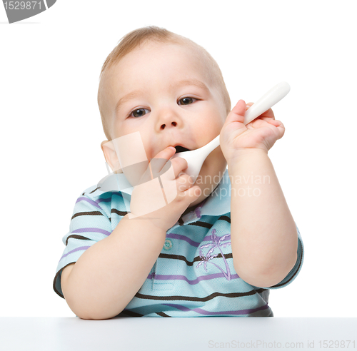 Image of Cute little boy is biting spoon