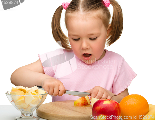 Image of Little girl is cutting fruits for salad