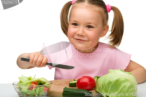 Image of Little girl is cutting carrot for salad