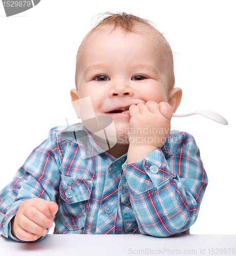 Image of Cute little boy is biting spoon