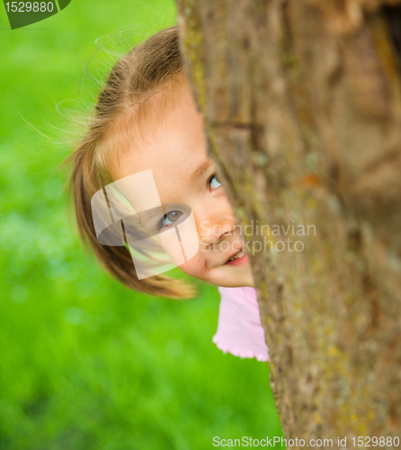 Image of Little girl is playing hide and seek outdoors