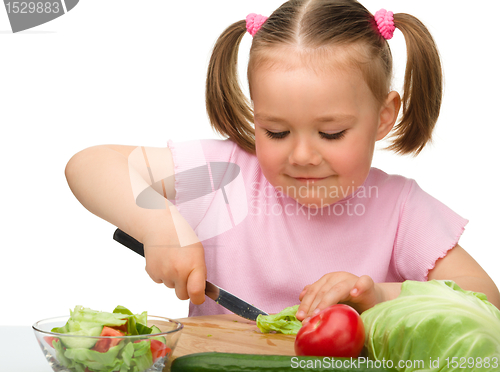 Image of Little girl is cutting carrot for salad