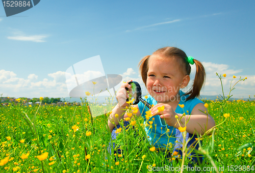 Image of Little girl examining flowers using magnifier