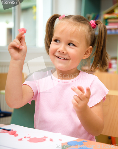 Image of Little girl is playing with plasticine