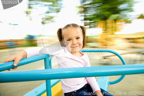 Image of Cute little girl is riding on merry-go-round