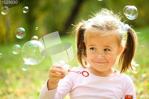 Image of Little girl is blowing a soap bubbles