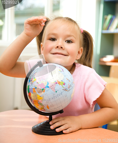 Image of Little girl is playing with globe