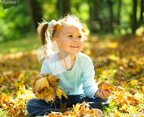 Image of Little girl is playing in autumn park