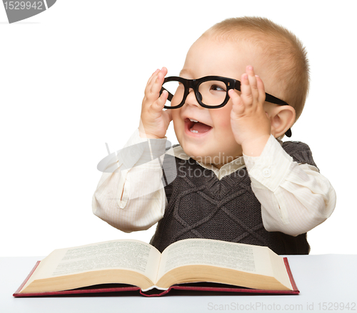 Image of Little child play with book and glasses
