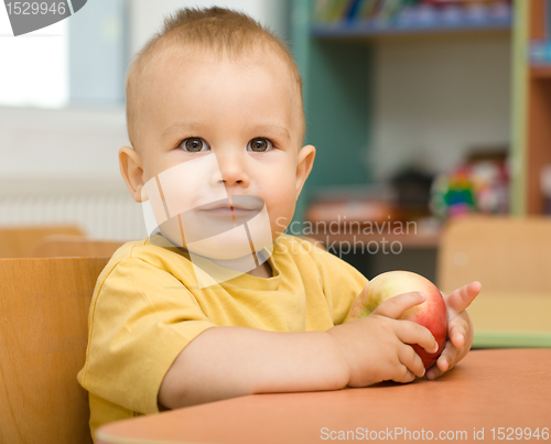 Image of Little boy is eating apple