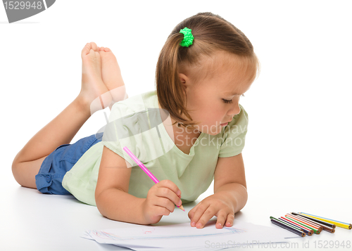 Image of Little girl is drawing while laying on the floor
