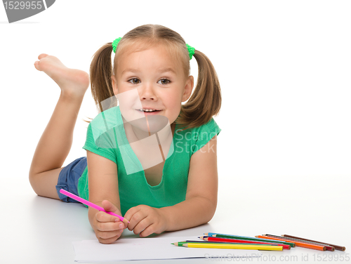 Image of Little girl is drawing while laying on the floor