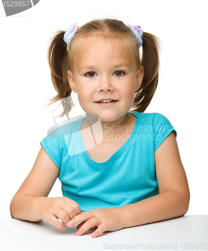 Image of Happy little girl is sitting at the table