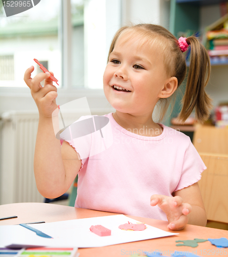 Image of Little girl is playing with plasticine