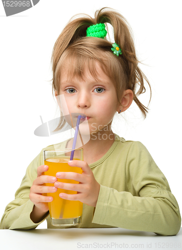 Image of Cute little girl is drinking orange juice