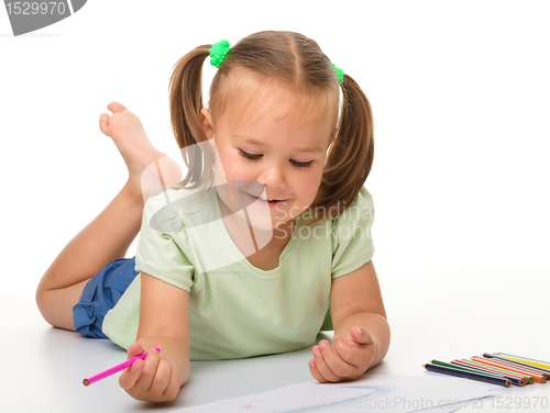 Image of Little girl is drawing while laying on the floor
