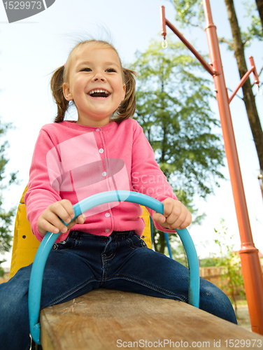 Image of Cute little girl is swinging on see-saw