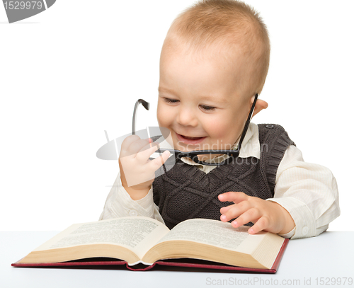 Image of Little child play with book and glasses