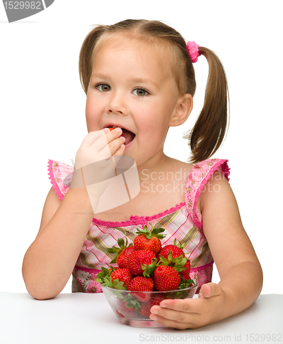 Image of Happy little girl eats strawberries