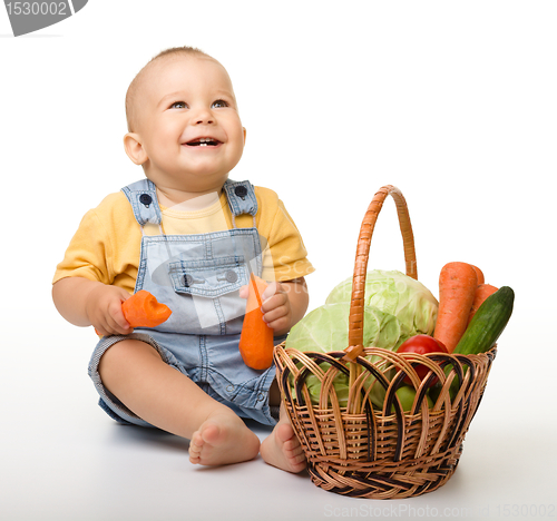 Image of Cute little boy with basket full of vegetables