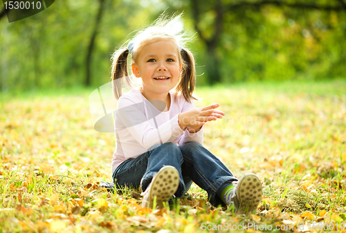 Image of Little girl is sitting on green meadow