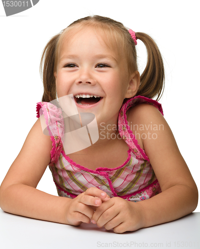 Image of Happy little girl is sitting at the table