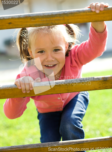 Image of Cute little girl is climbing up on ladder