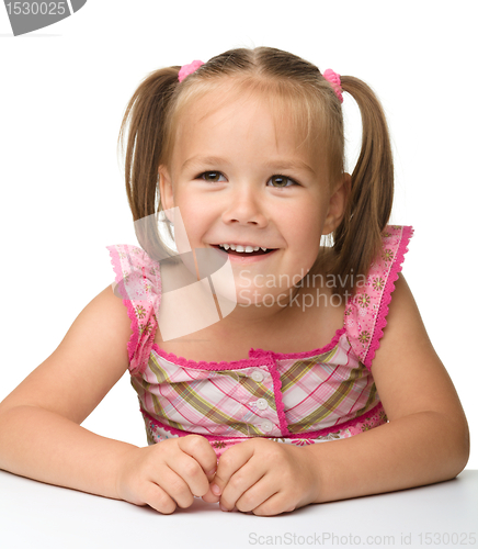 Image of Happy little girl is sitting at the table