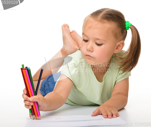 Image of Little girl is drawing while laying on the floor