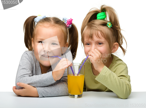 Image of Two little girls are drinking orange juice