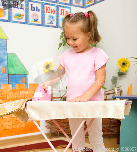 Image of Little girl is playing with iron