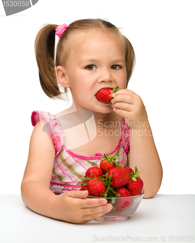 Image of Happy little girl eats strawberries