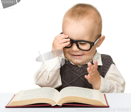 Image of Little child play with book and glasses