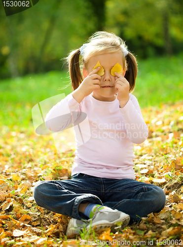 Image of Little girl is playing in autumn park