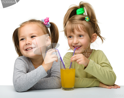 Image of Two little girls are drinking orange juice