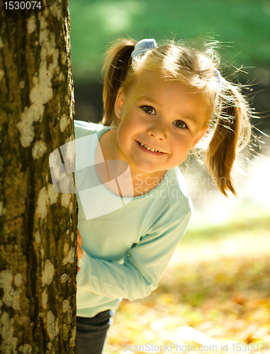 Image of Little girl is playing in autumn park