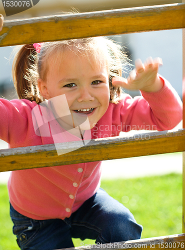 Image of Cute little girl is climbing up on ladder