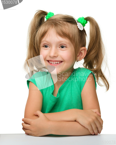 Image of Happy little girl is sitting at the table