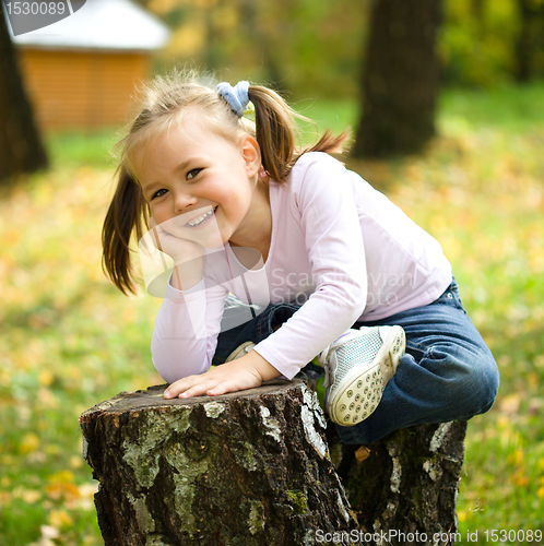Image of Little girl is playing in autumn park