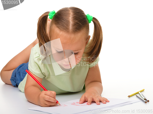 Image of Little girl is drawing while laying on the floor