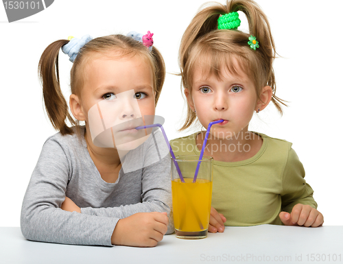 Image of Two little girls are drinking orange juice